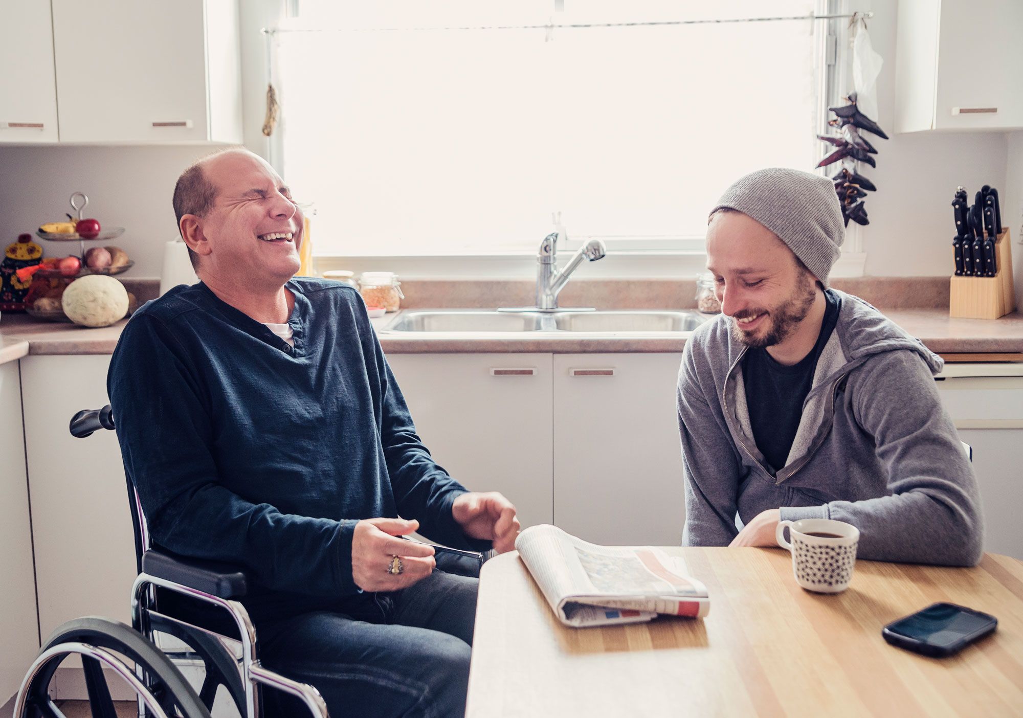 two men laughing at home during coffee